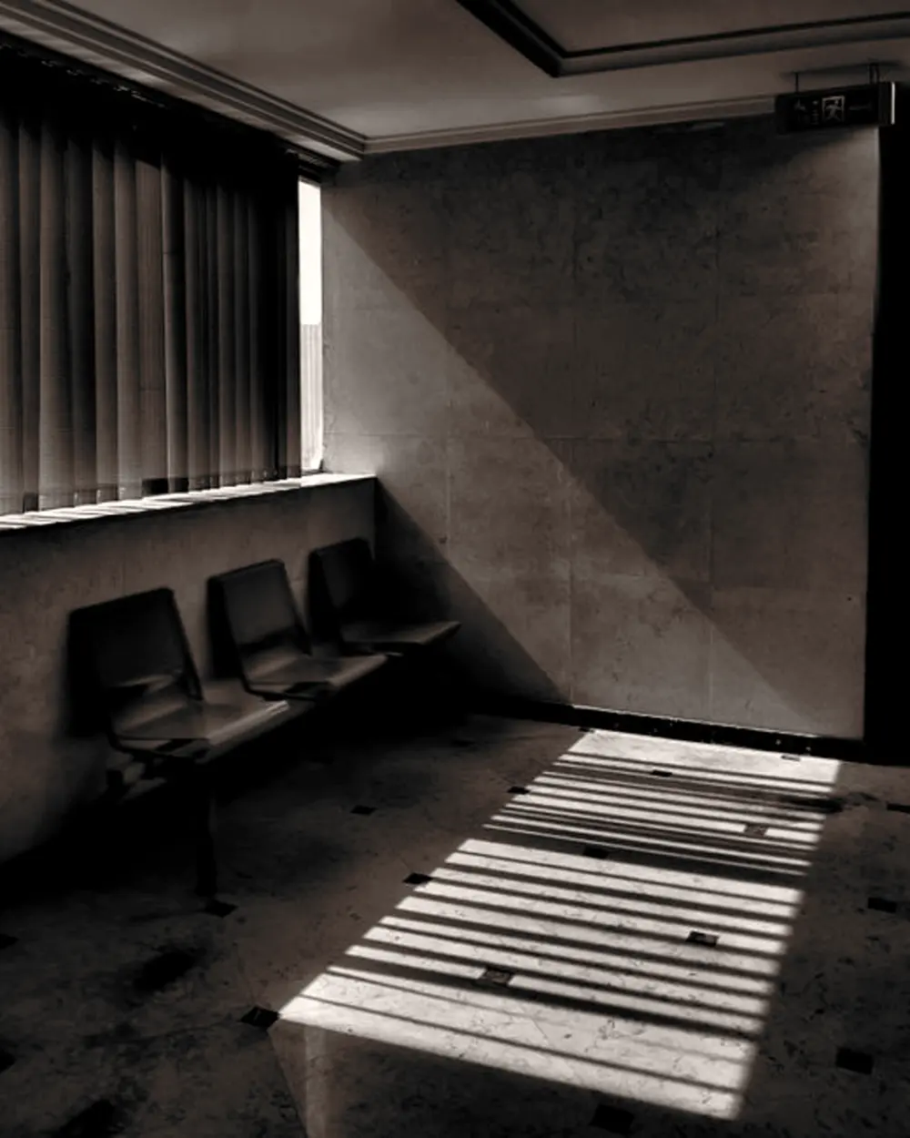 Une salle d'attente vide, la lumière d'une persienne posée au sol.