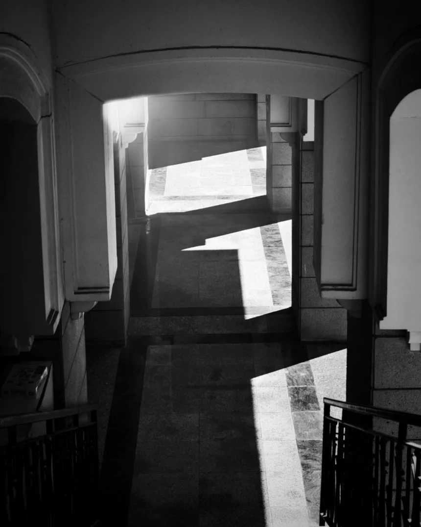 Un couloir de pierre éclairé par une ouverture, les ombres portées au sol.