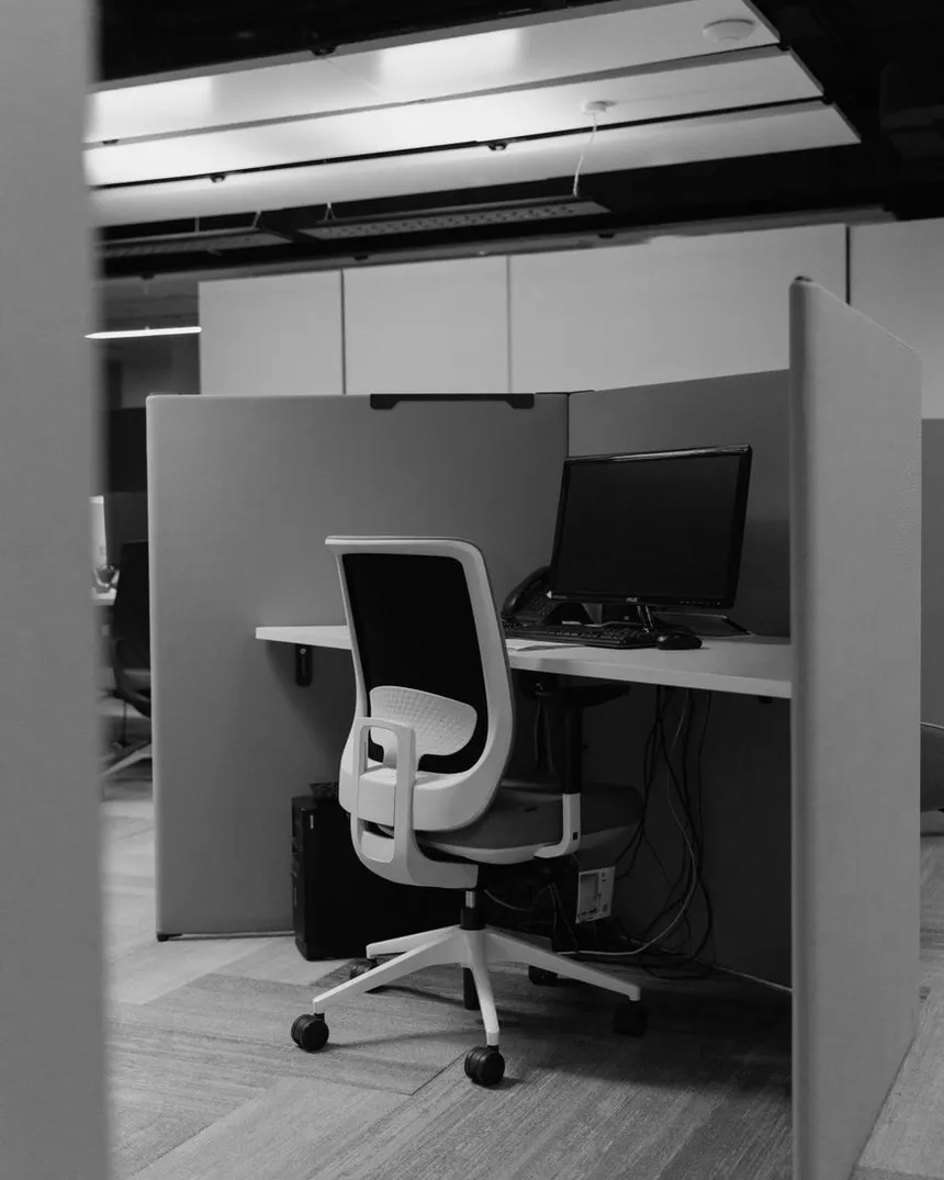Un poste de travail vide derrière une cloison, dans un bureau désert.